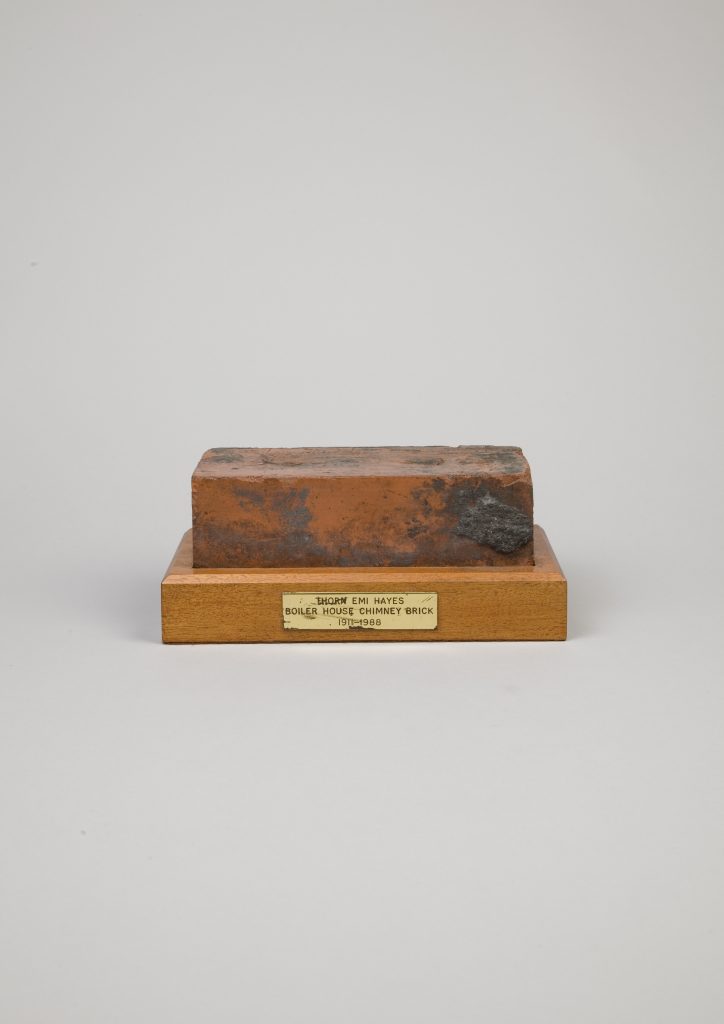 Hayes Factory Brick This is a red brick from The Gramophone Company's Boiler House at the Hayes Factory. It has been waxed and mounted on a wood plinth. The brass plaque reads ‘Thorn EMI Hayes Boiler House Chimney Brick 1911-1988’ Date: 1911 Photographer: www.thomasbutlerphotographer.com